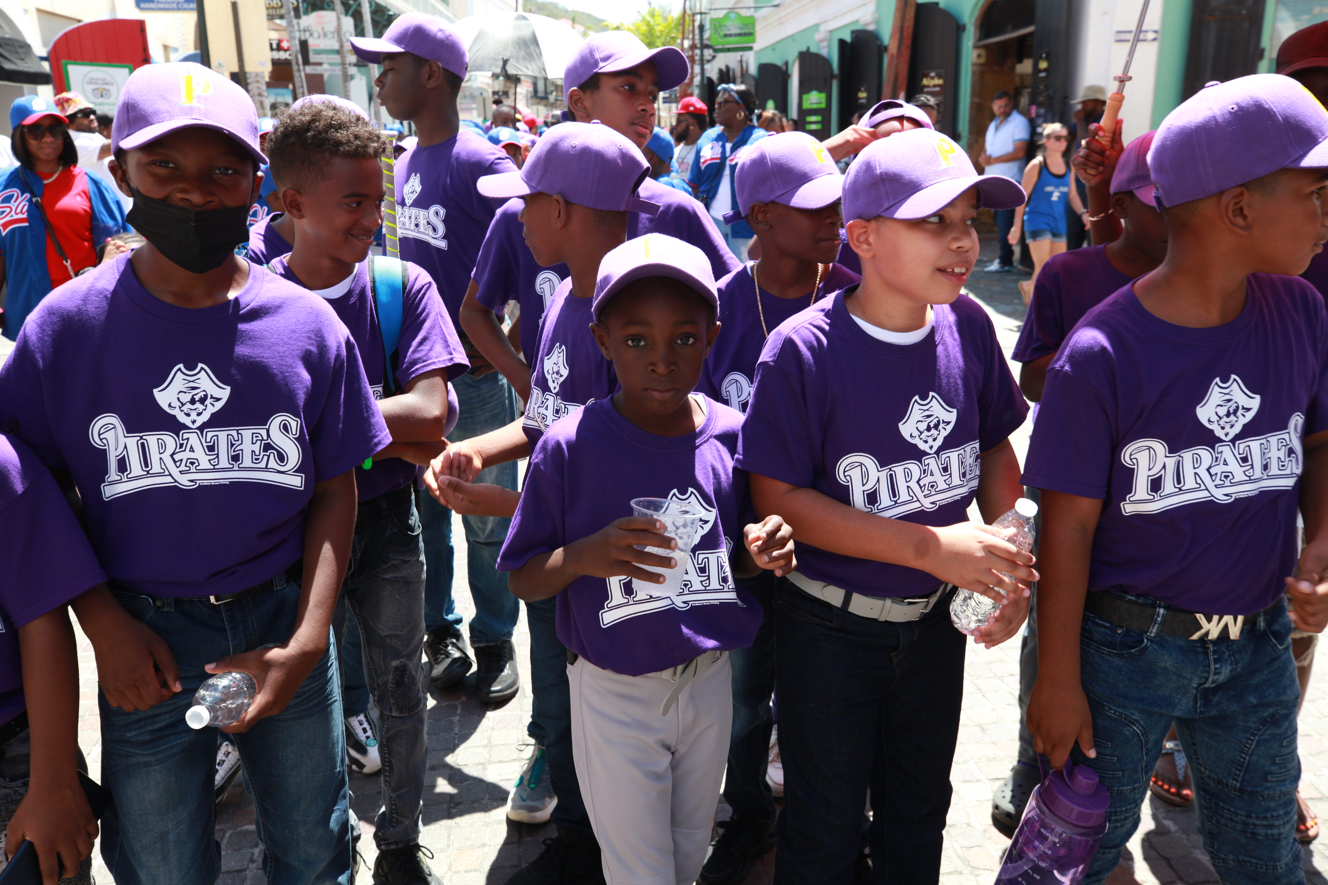 Youth players in uniform move through St. Thomas during the Little League opening day parade.