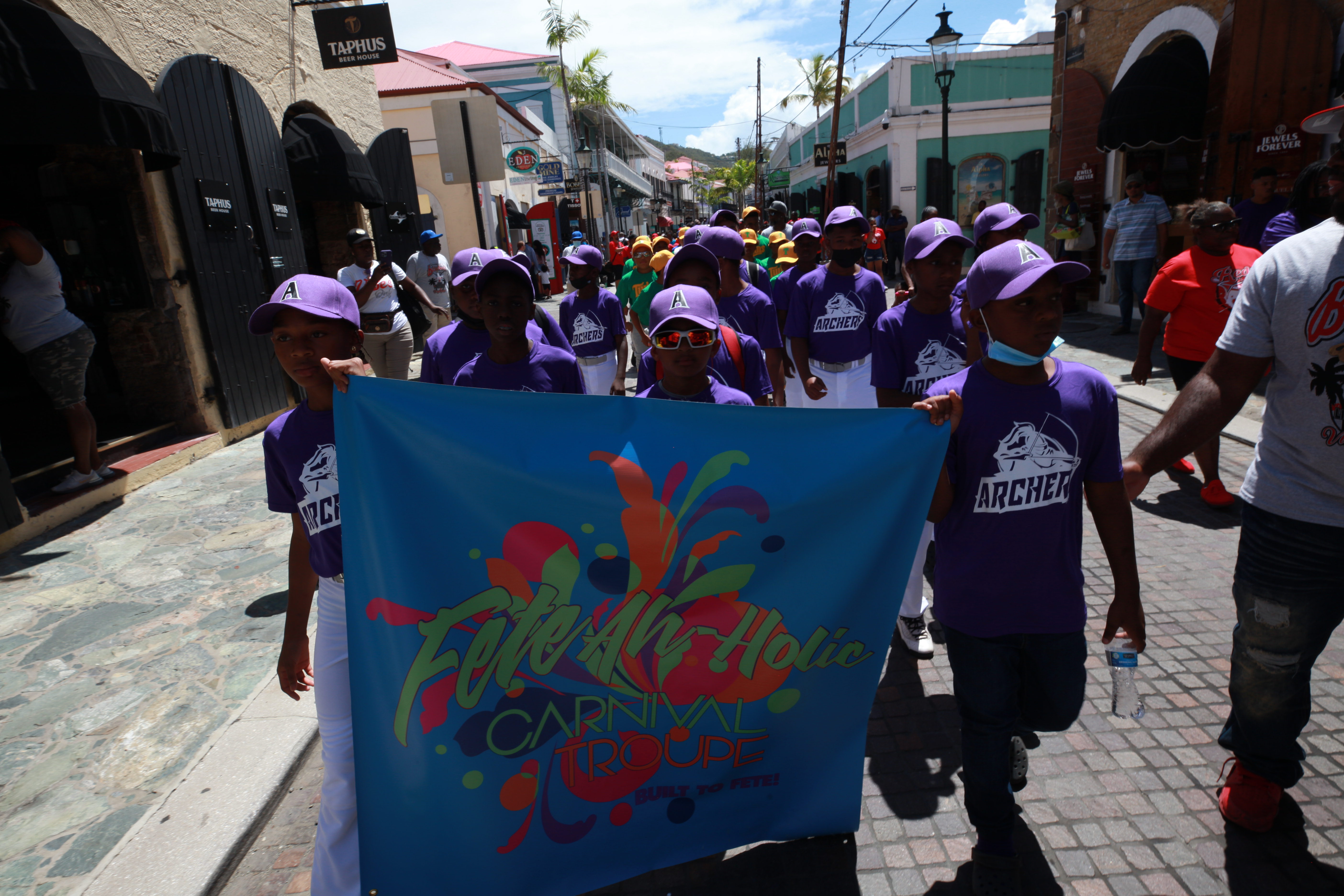 Little League players march in the opening day parade through St. Thomas with a team banner.