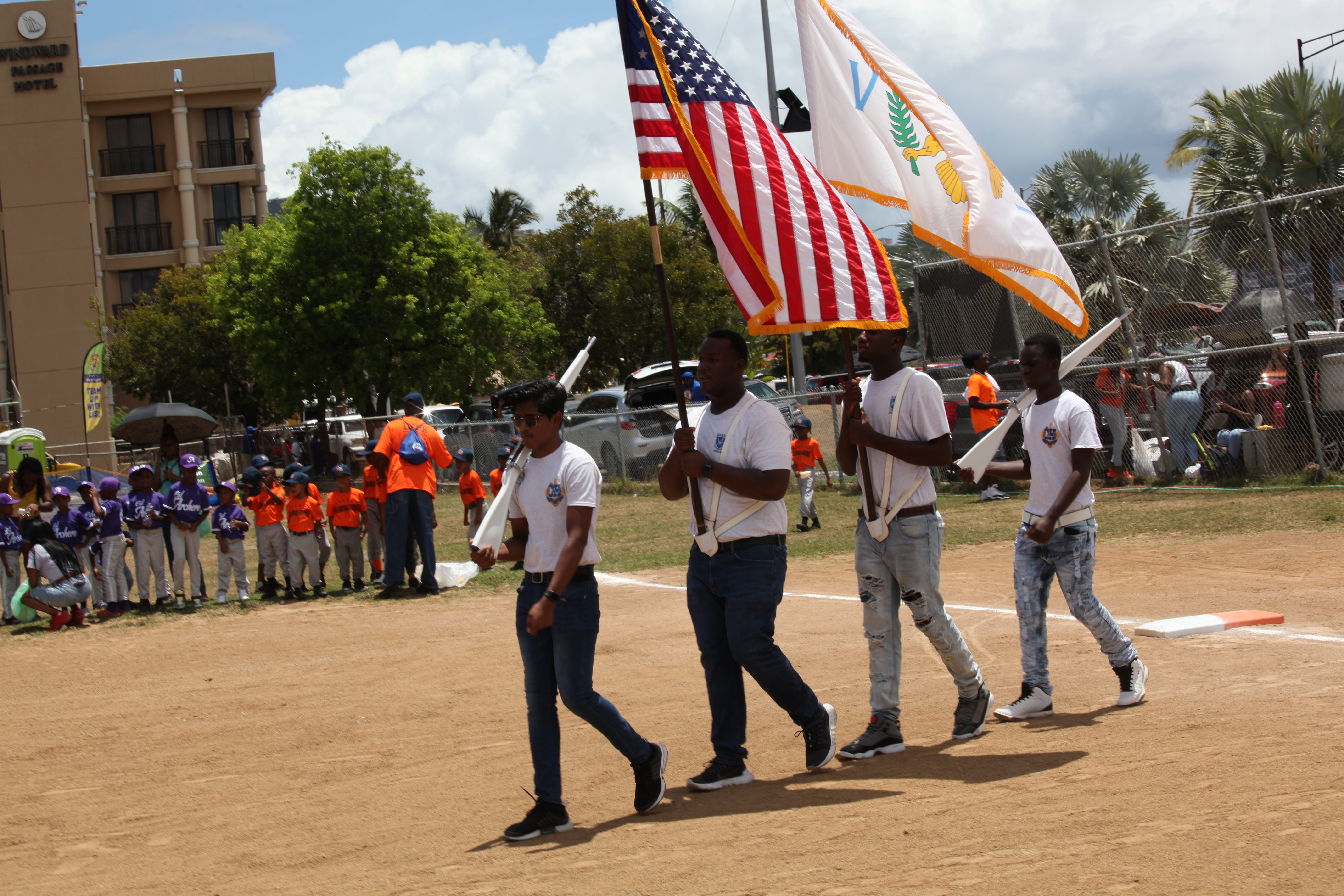 Participants carry flags across Griffith Ballpark during Little League opening ceremonies in St. Thomas.