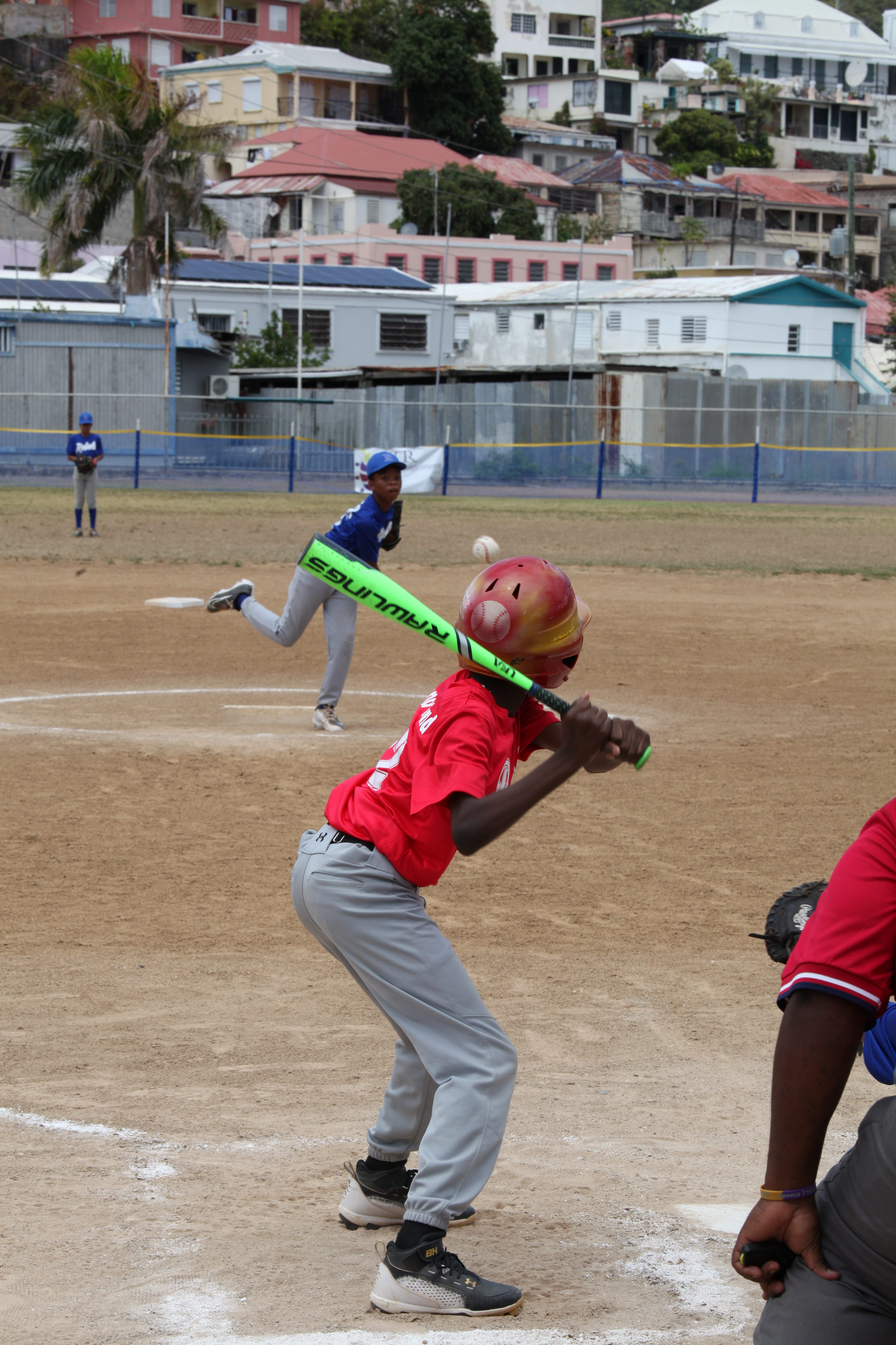 A red-uniform batter settles into the box as opening day Little League play continues at Griffith Ballpark.