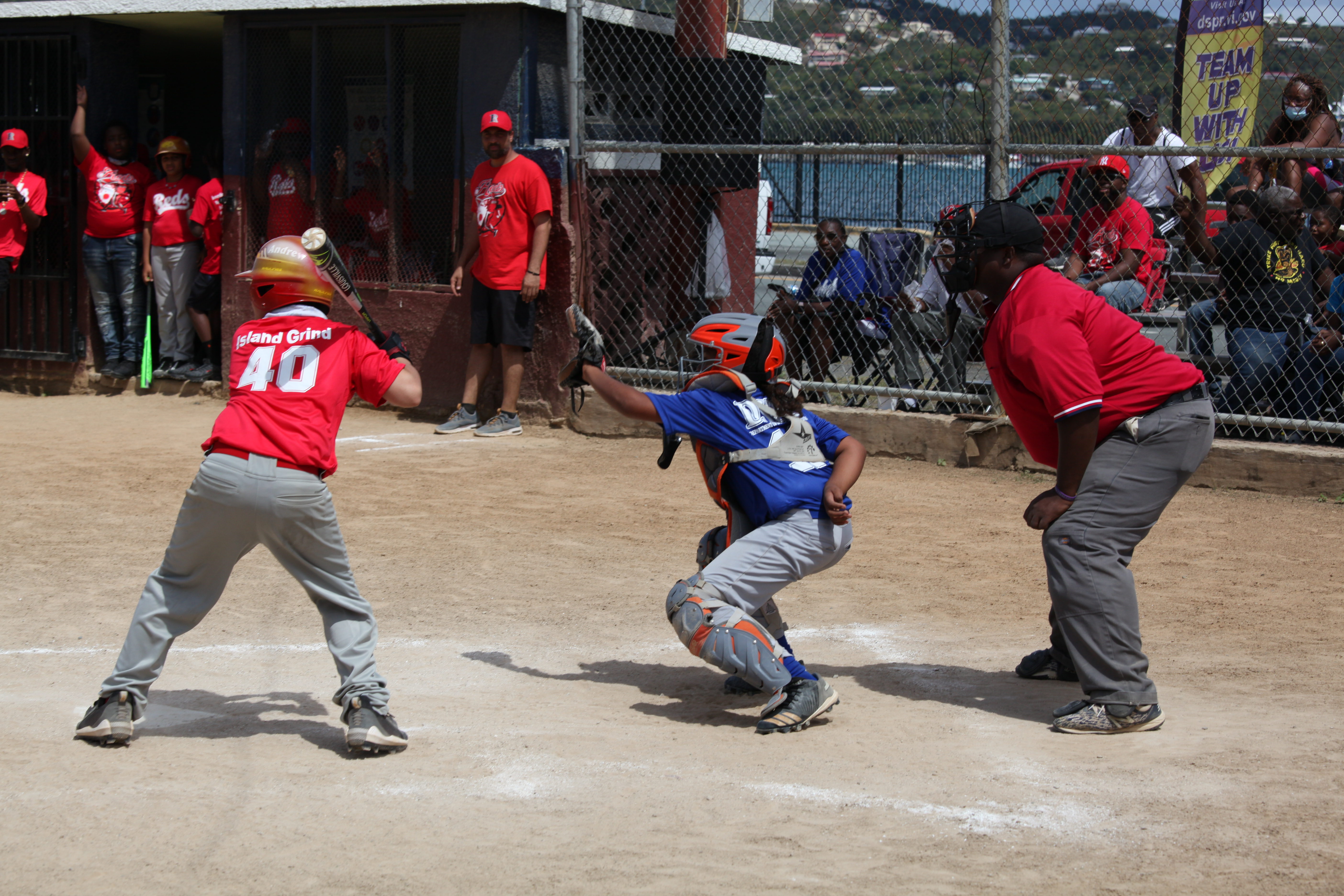 A Little League batter waits at the plate as the catcher and umpire set for the next pitch at Griffith Ballpark.