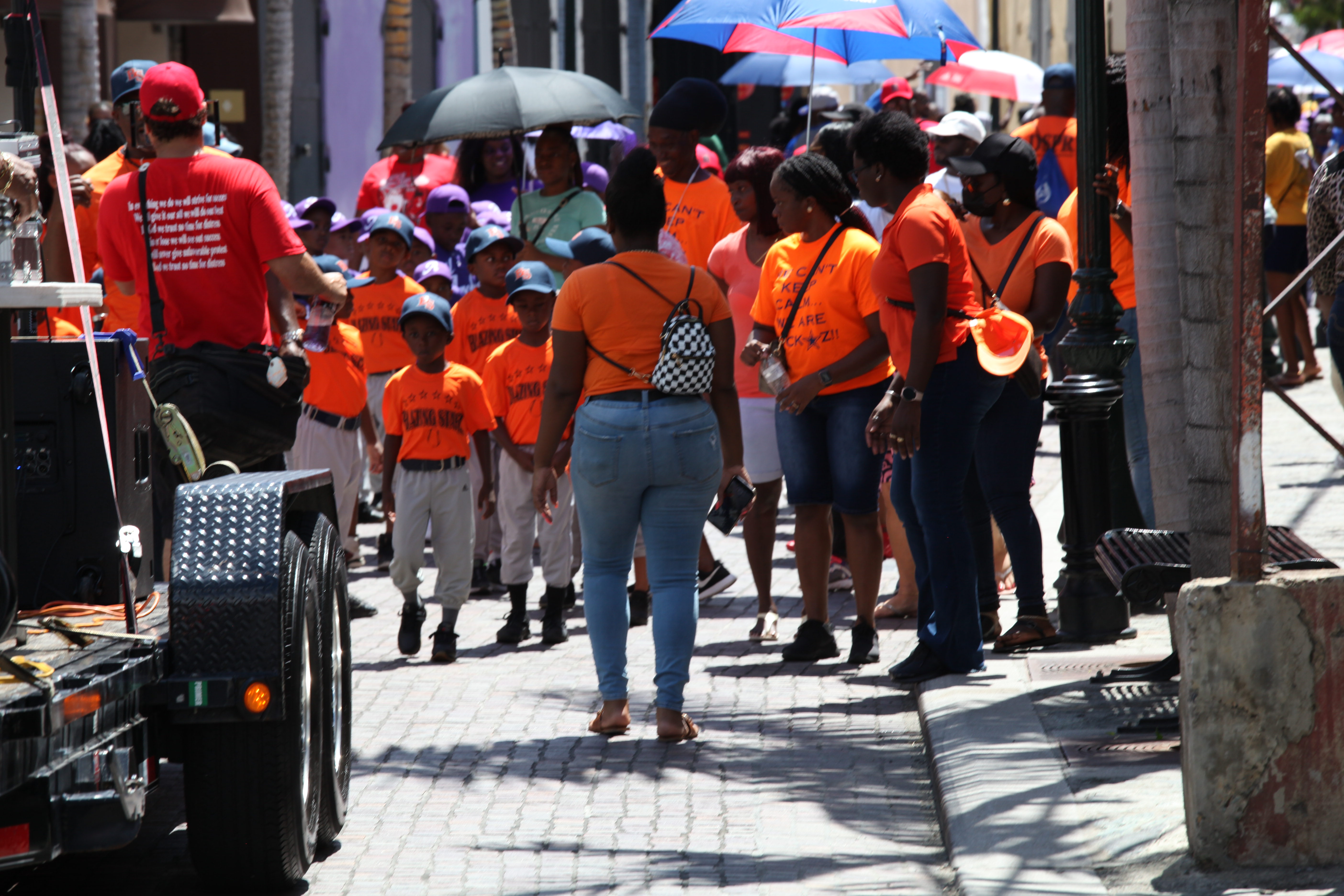 Orange-shirted youth march through St. Thomas during the Little League opening day parade.