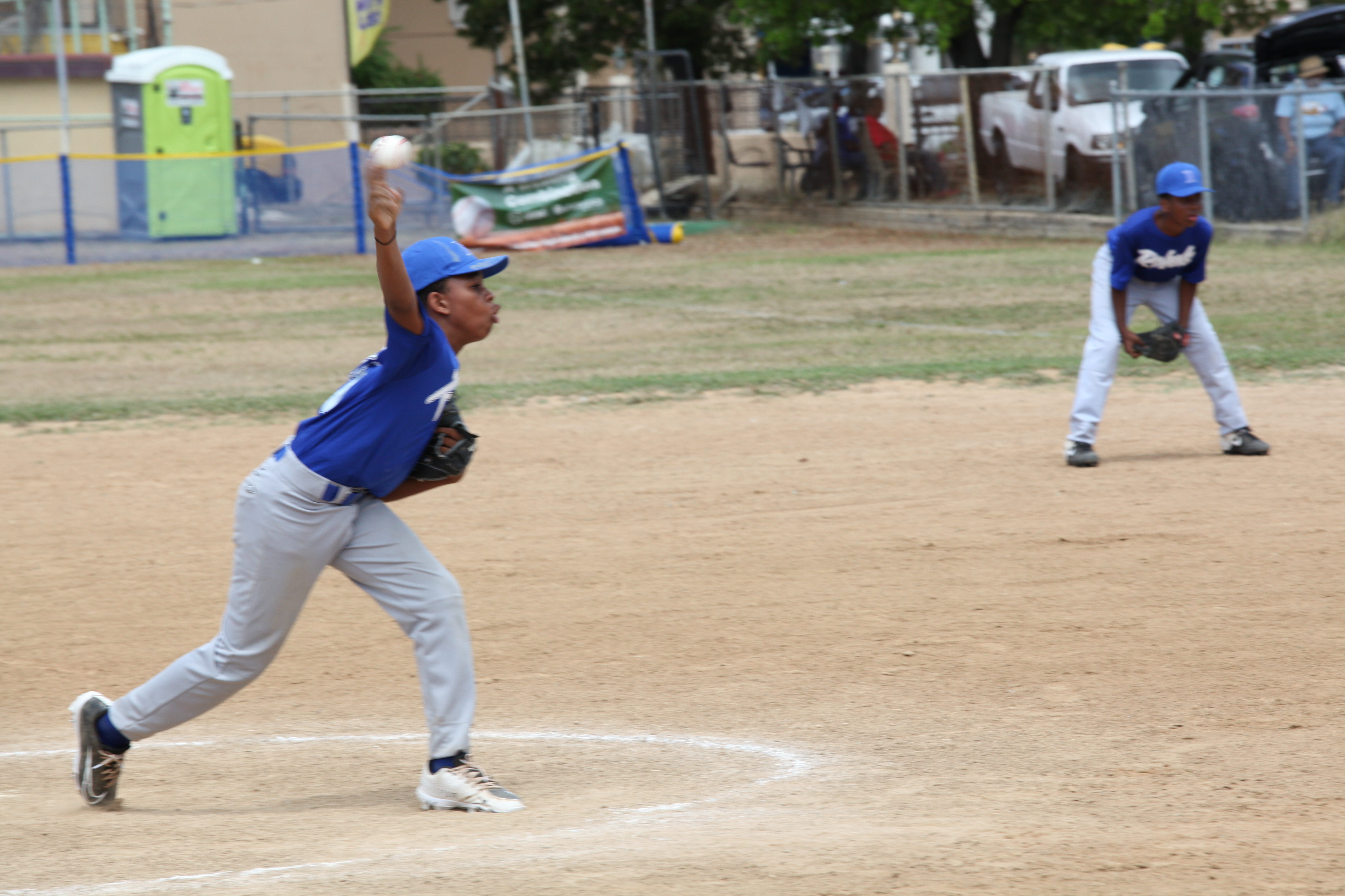 A blue-uniform pitcher delivers a pitch during Little League opening day action in St. Thomas.