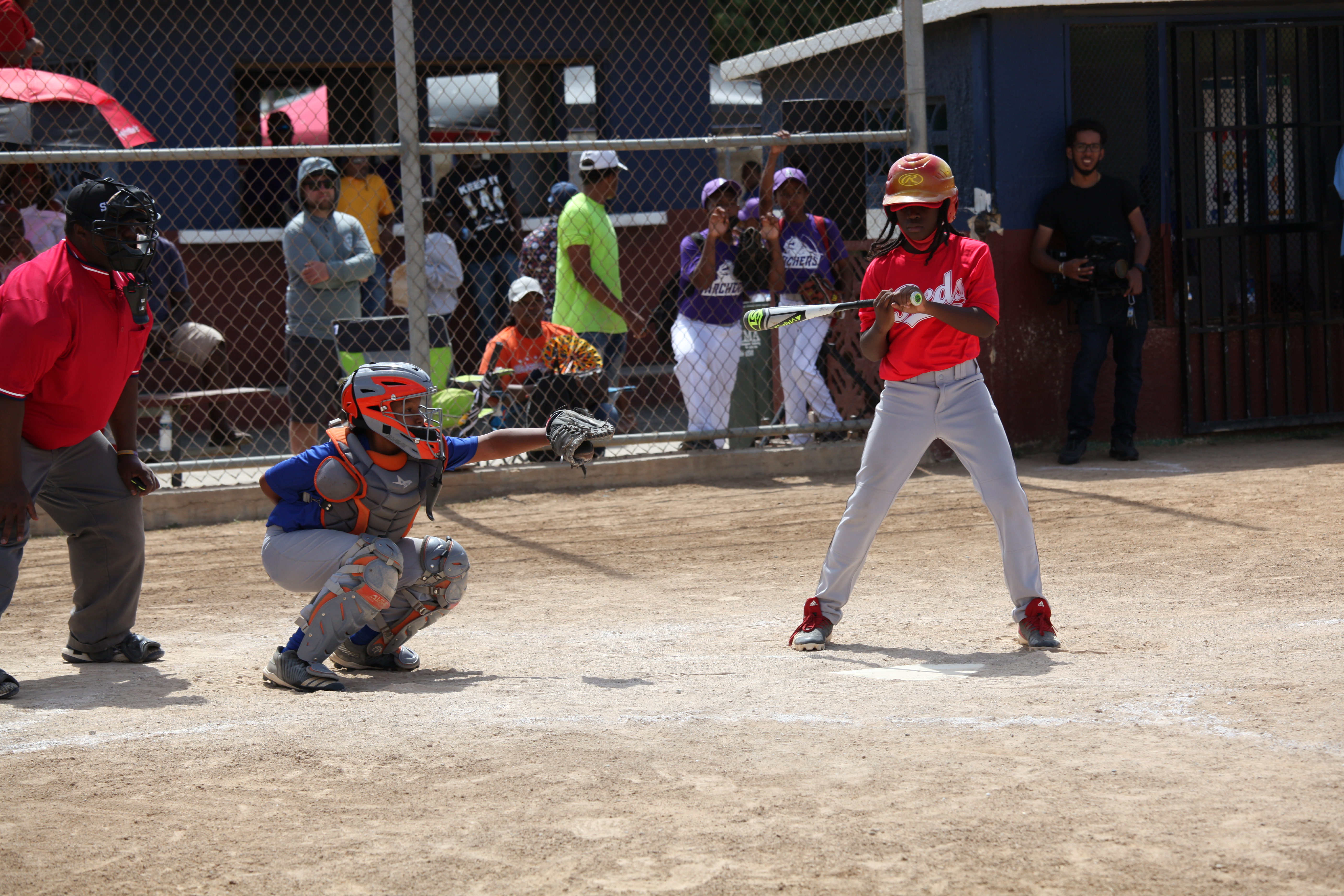 A Little League batter waits for the next pitch as the catcher sets up behind the plate in St. Thomas.