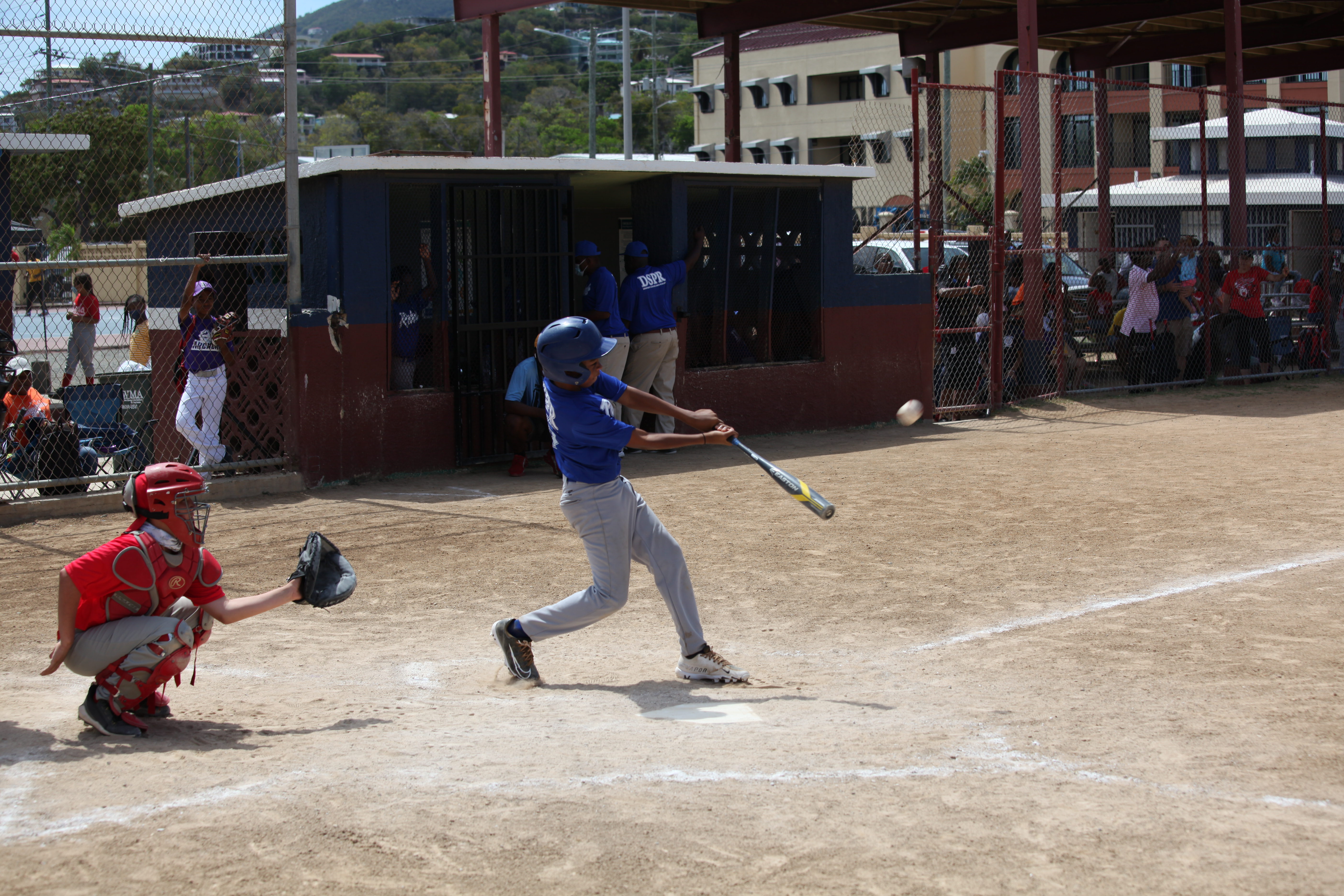 A blue-uniform Little League batter steps into the box during opening day play at Griffith Ballpark.