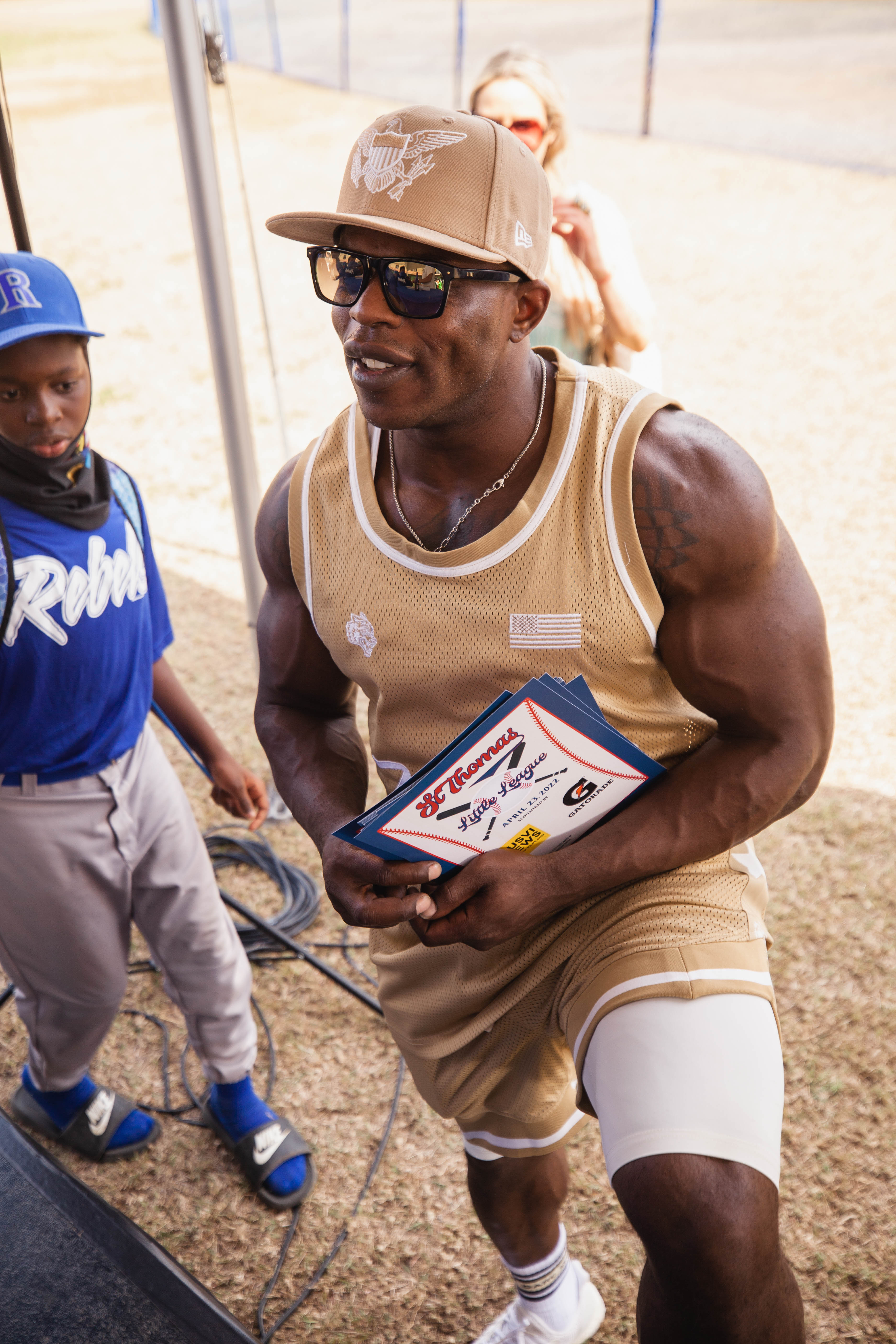 Andre Ferguson holds papers beside a youth baseball player.
