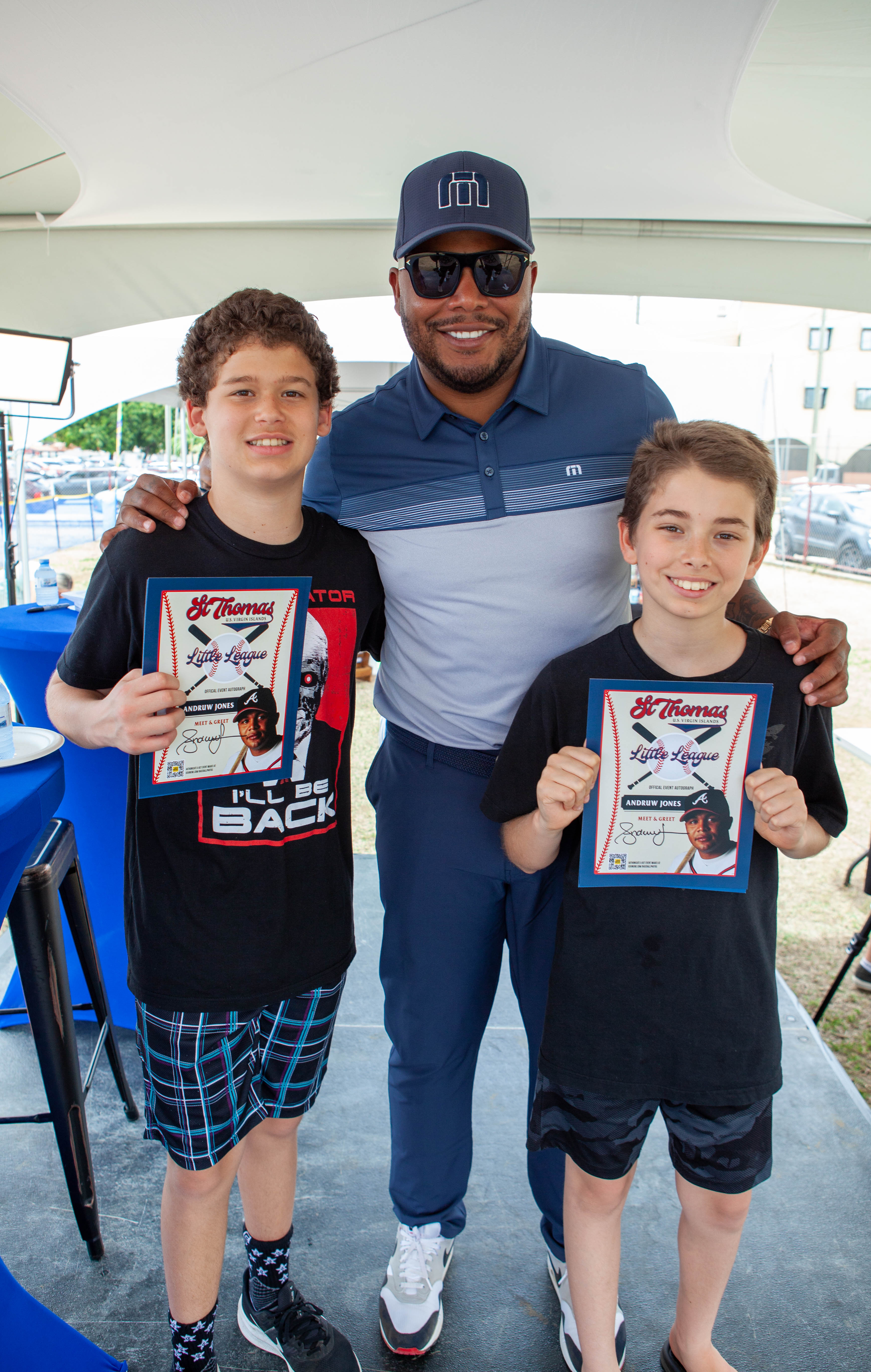 Andruw Jones poses with two boys holding framed pictures.