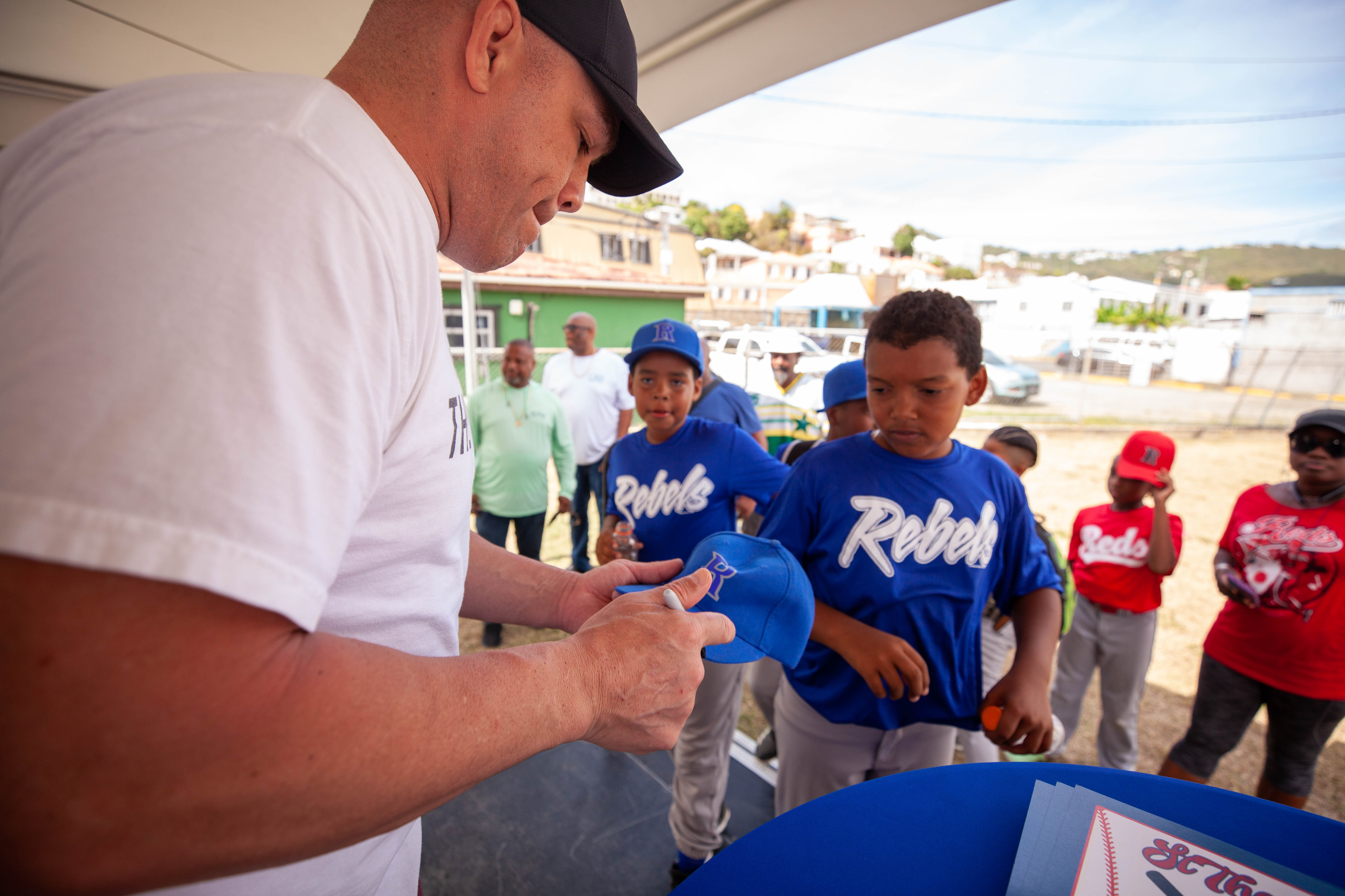 Tito Ortiz signs an item for youth players under a tent.