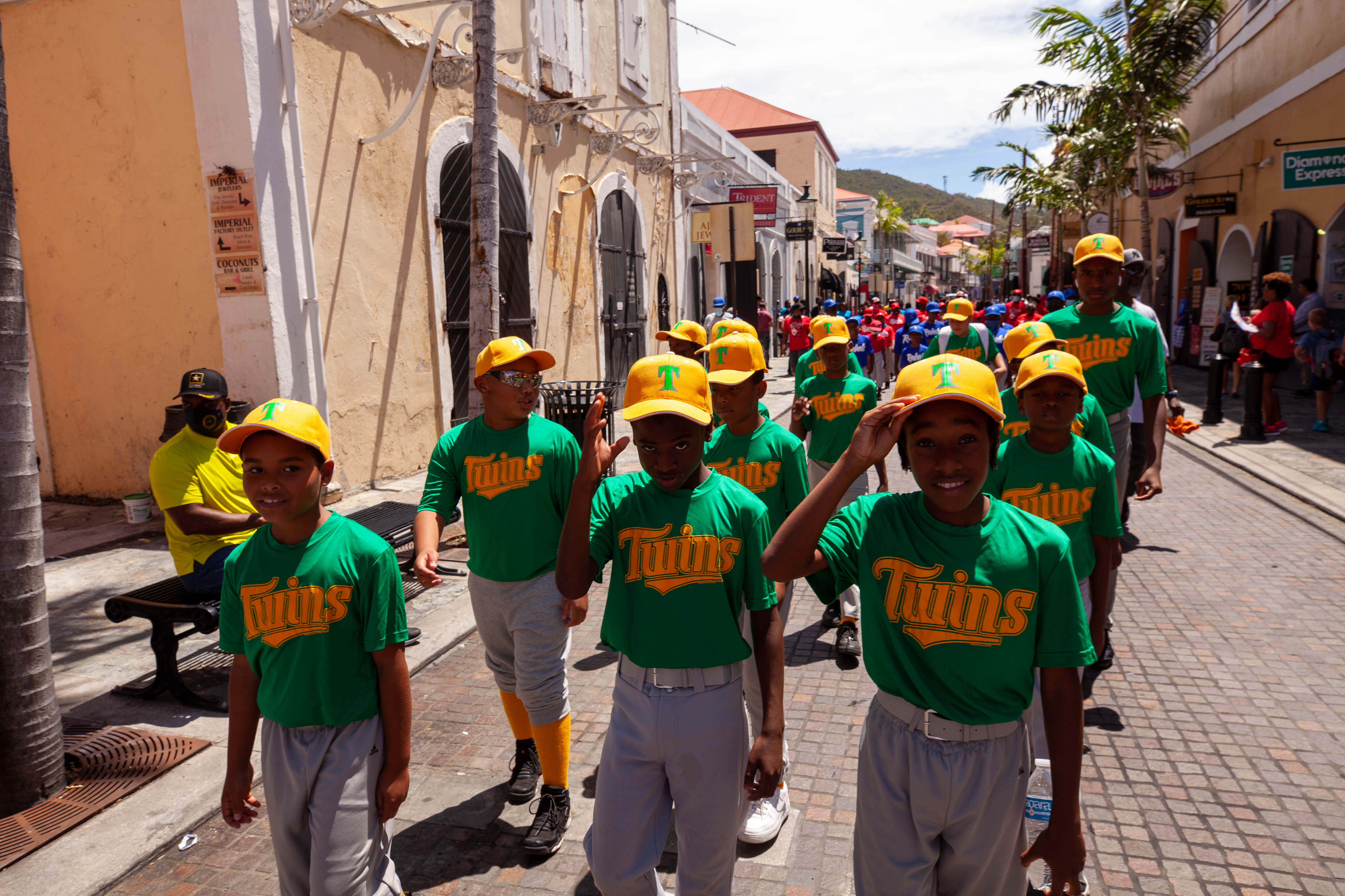 Twins youth baseball team walks down a cobblestone street.