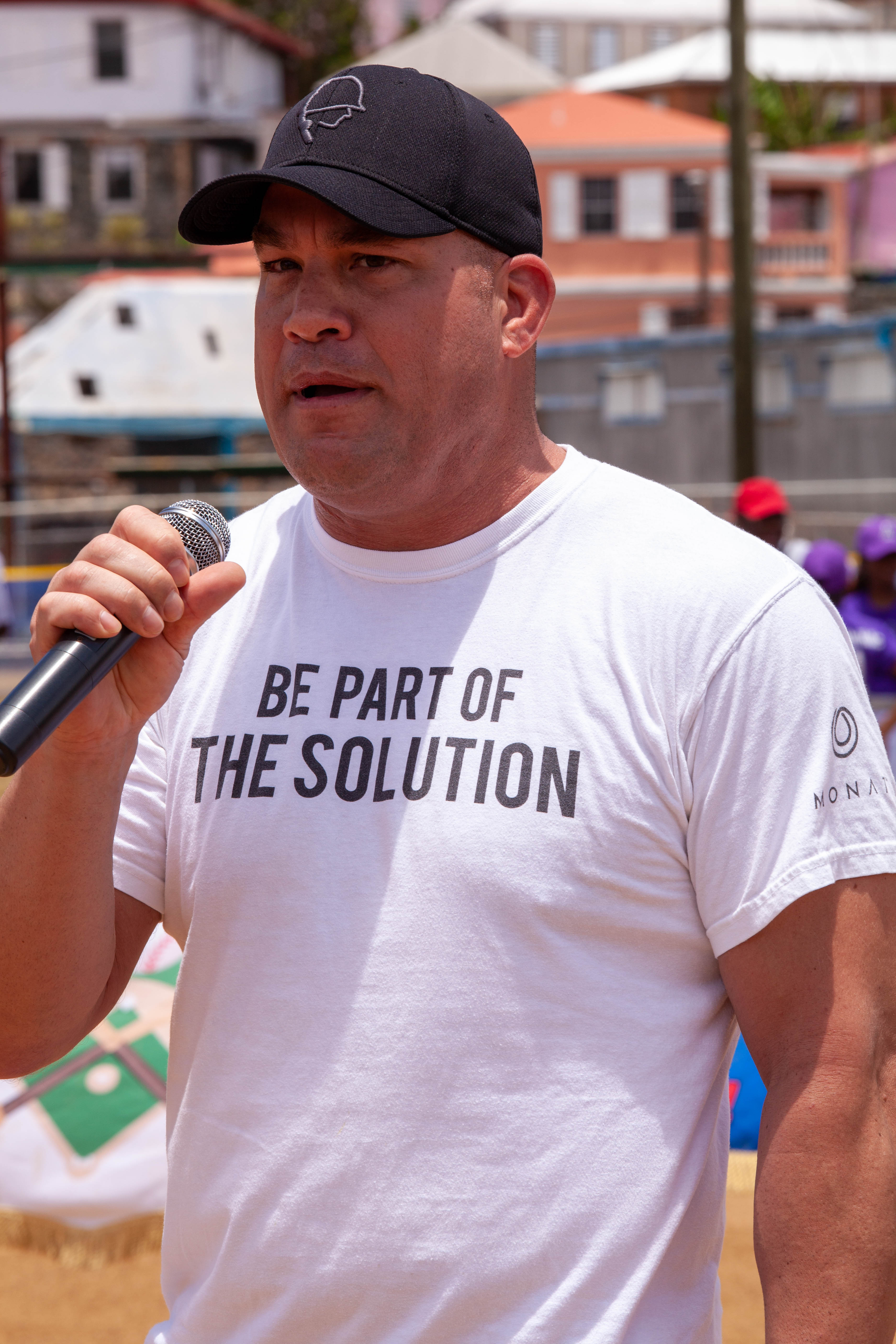 Tito Ortiz speaks into a microphone wearing a white slogan shirt.
