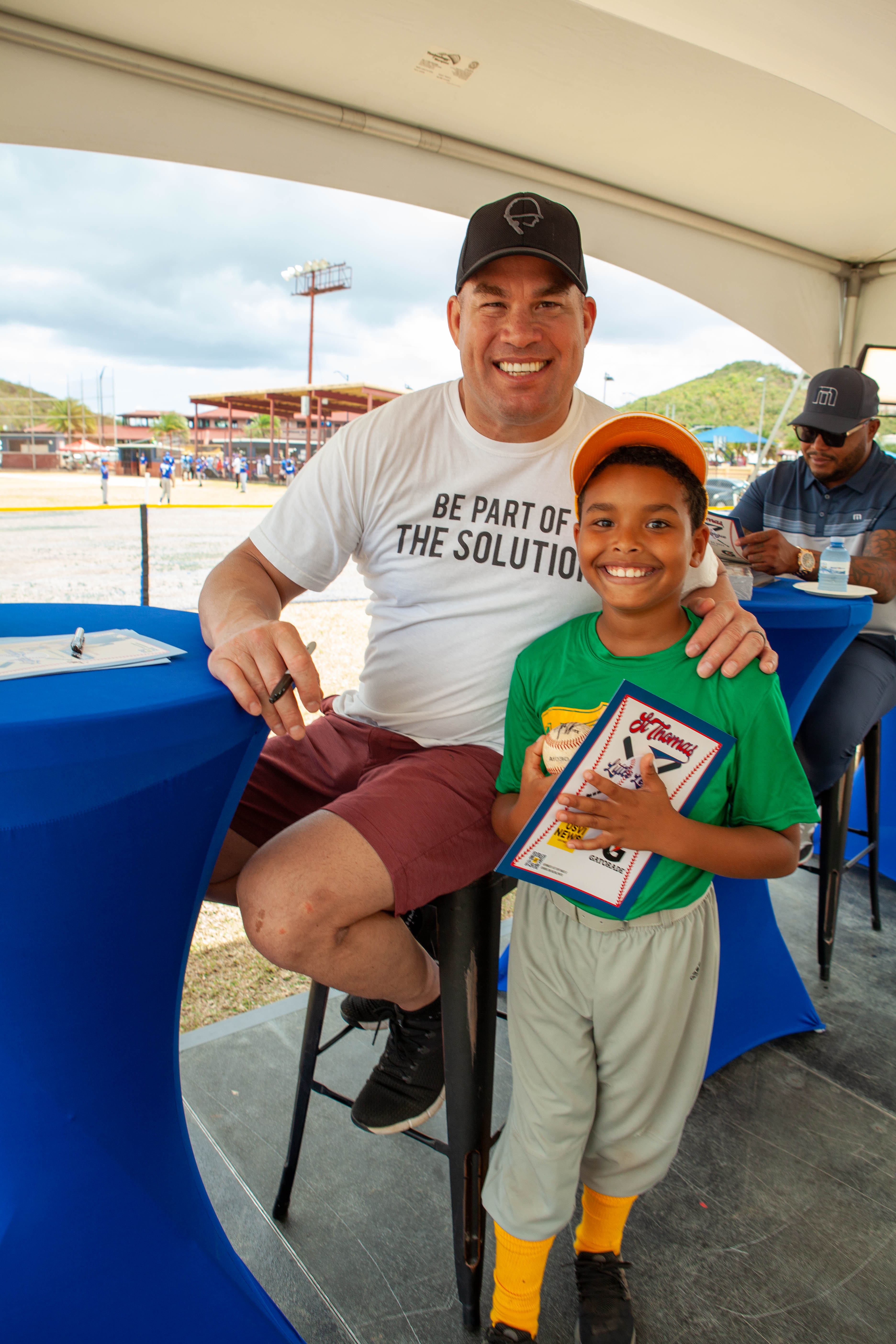 Tito Ortiz poses with a smiling young player holding a certificate.
