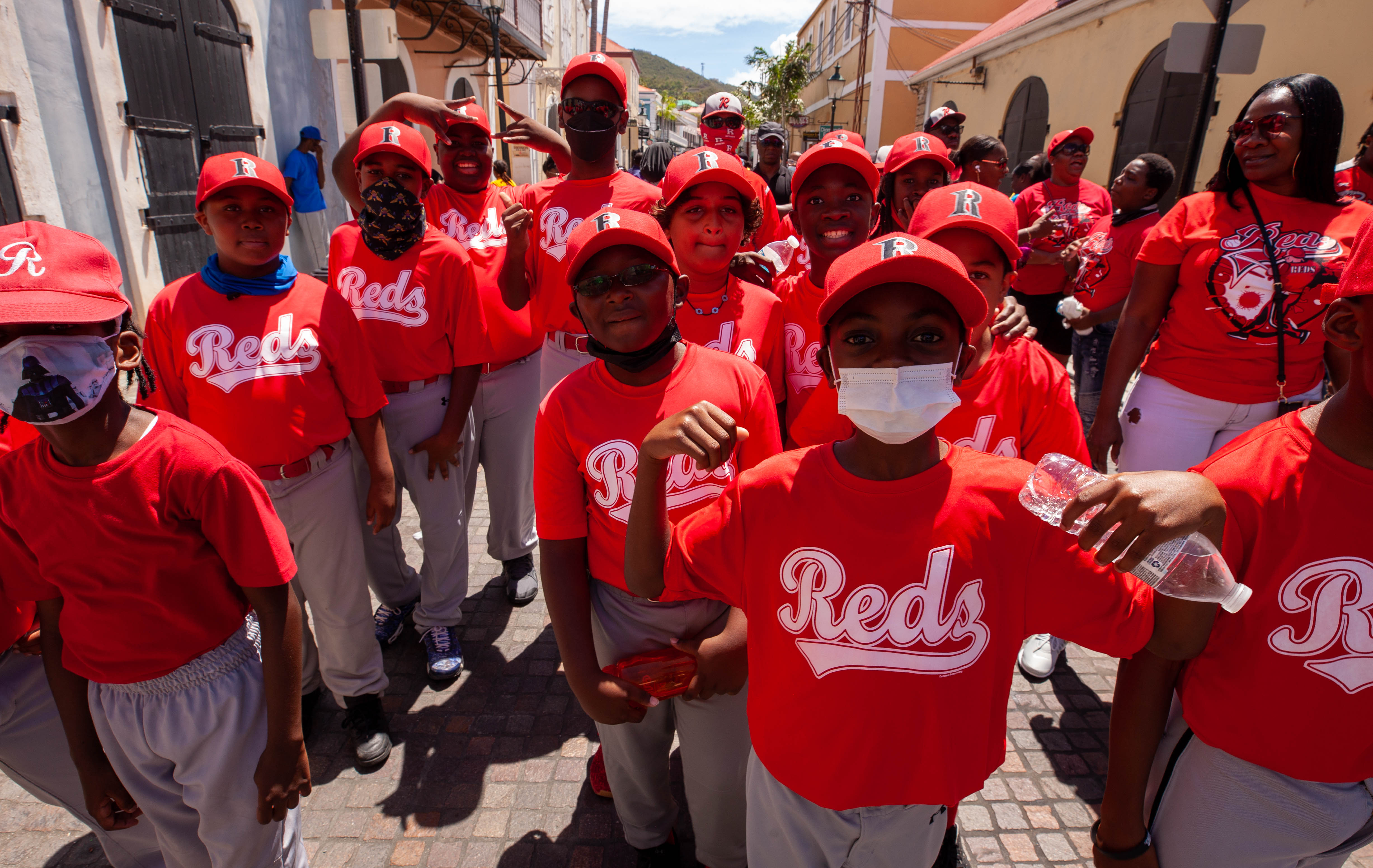 Reds youth baseball team walks together in a street parade.