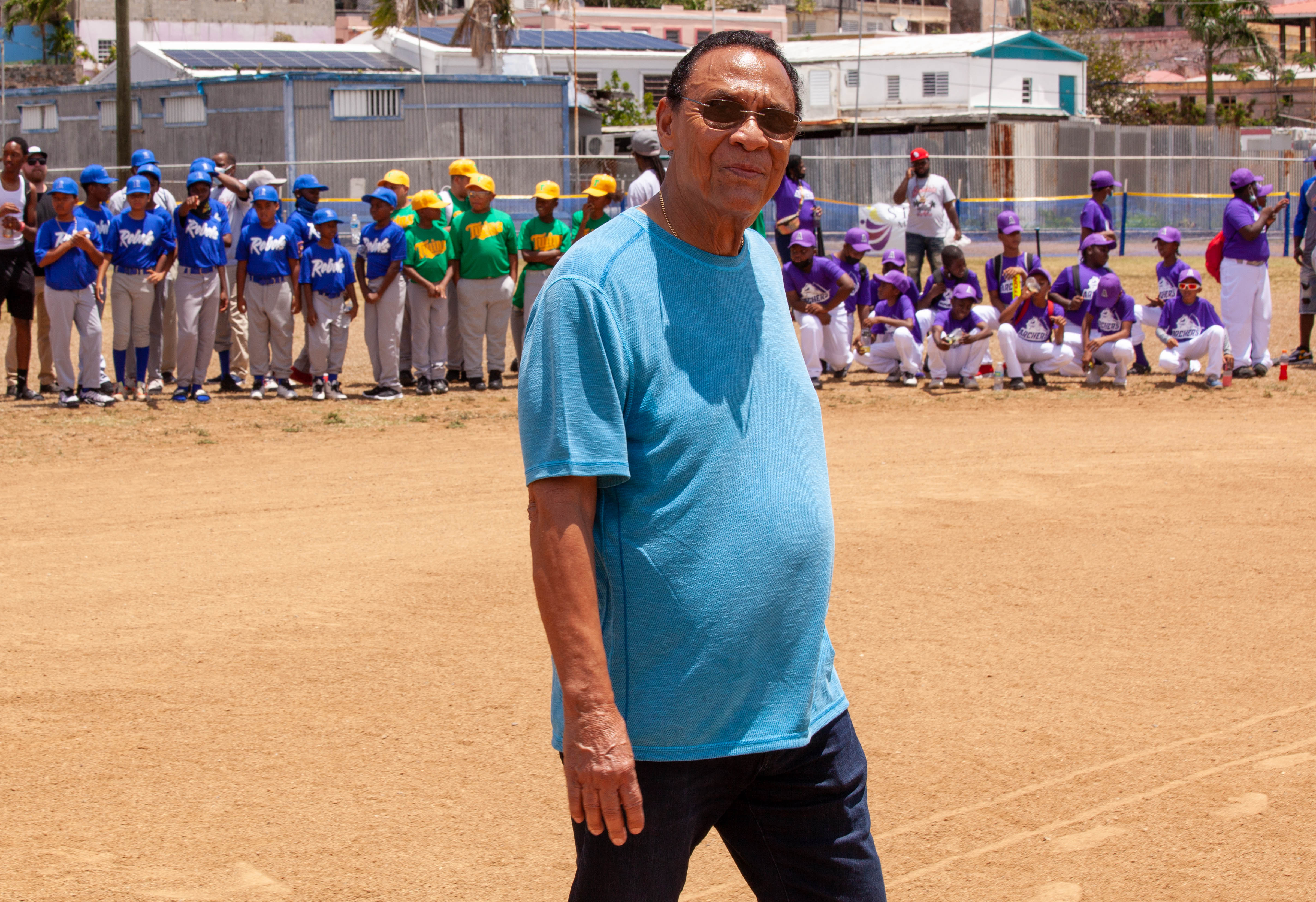 Tony Perez stands on the field with youth teams lined up behind him.