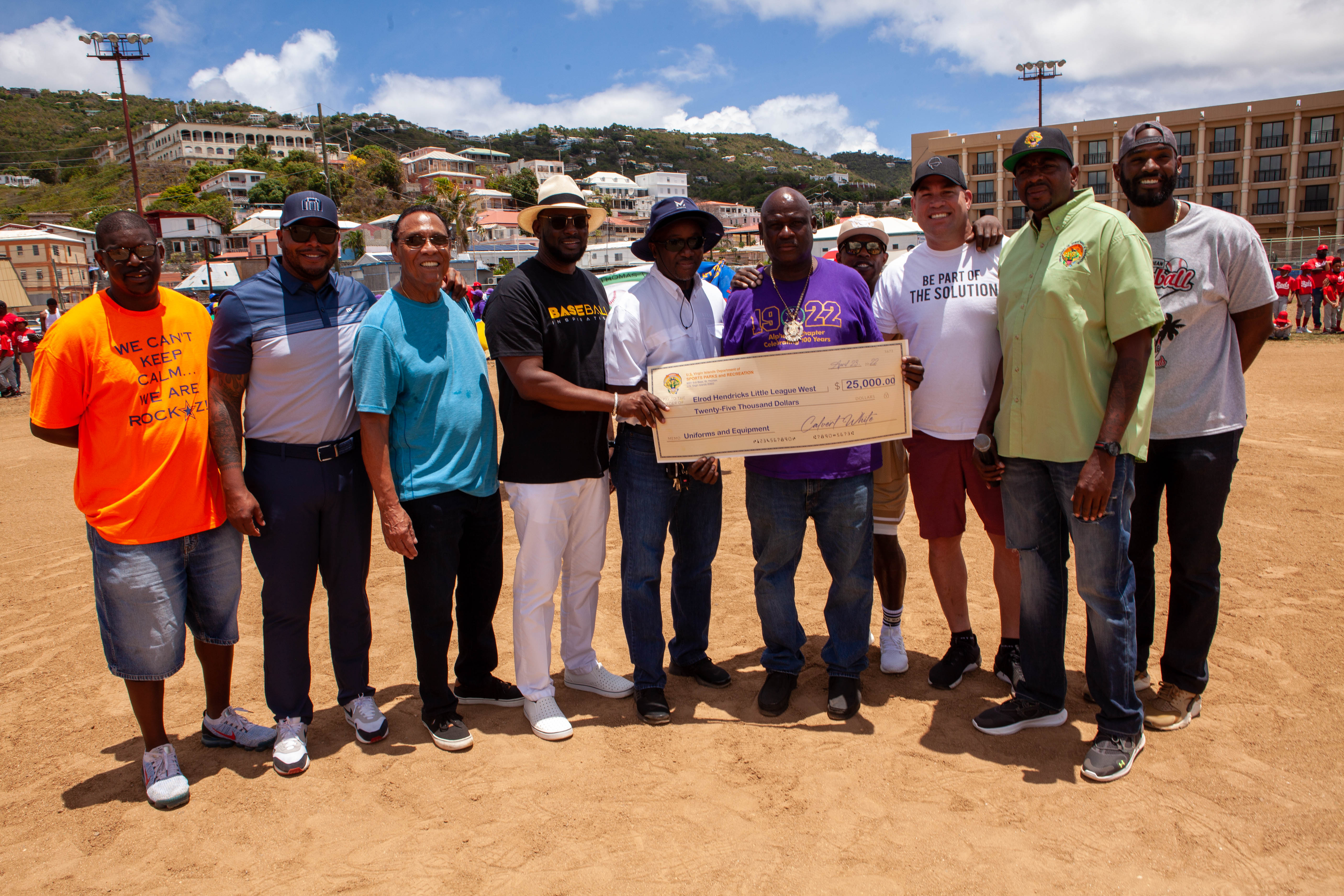 Group poses on the field with a ceremonial check.