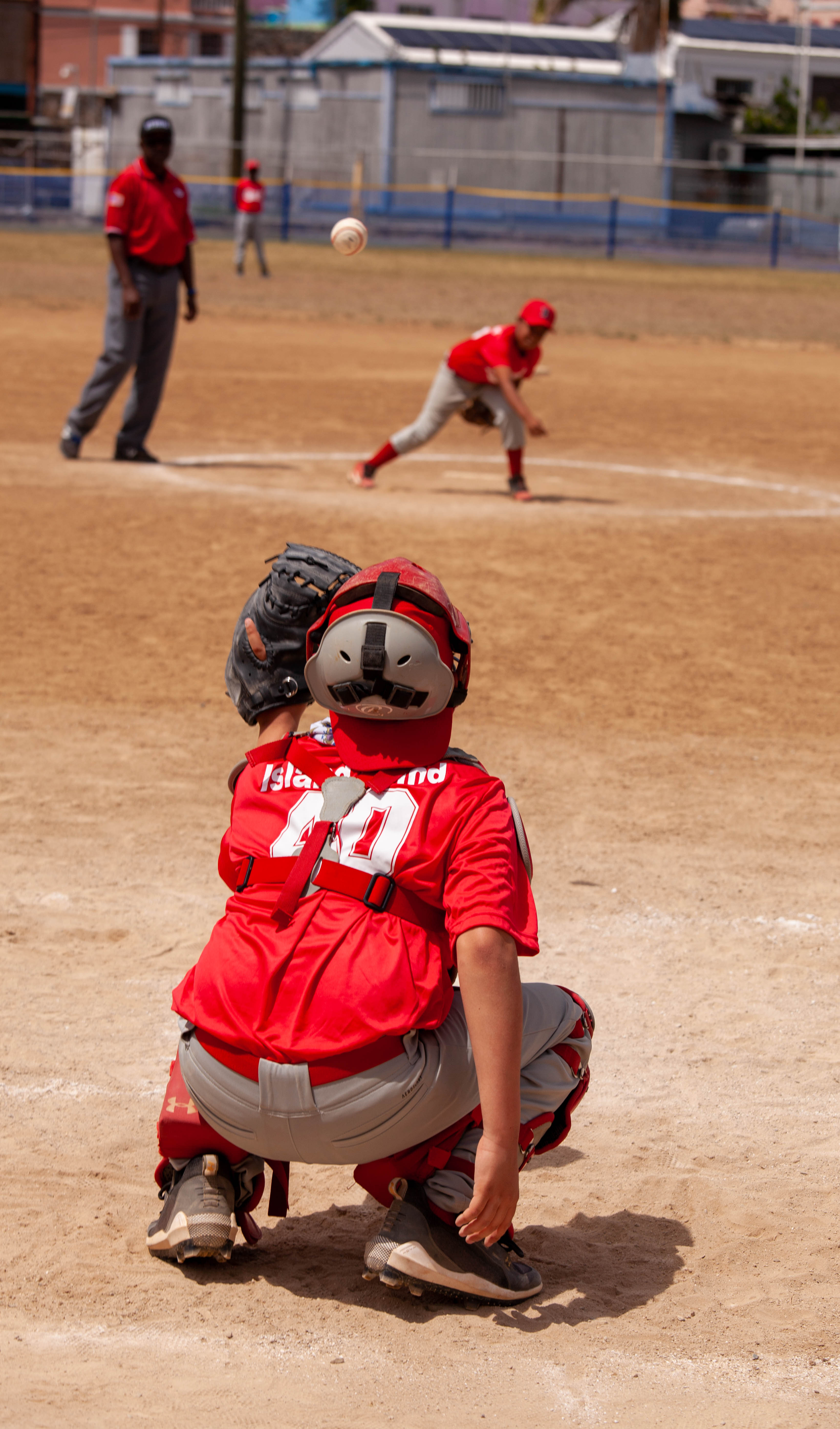 Catcher crouches behind home plate during youth baseball game.