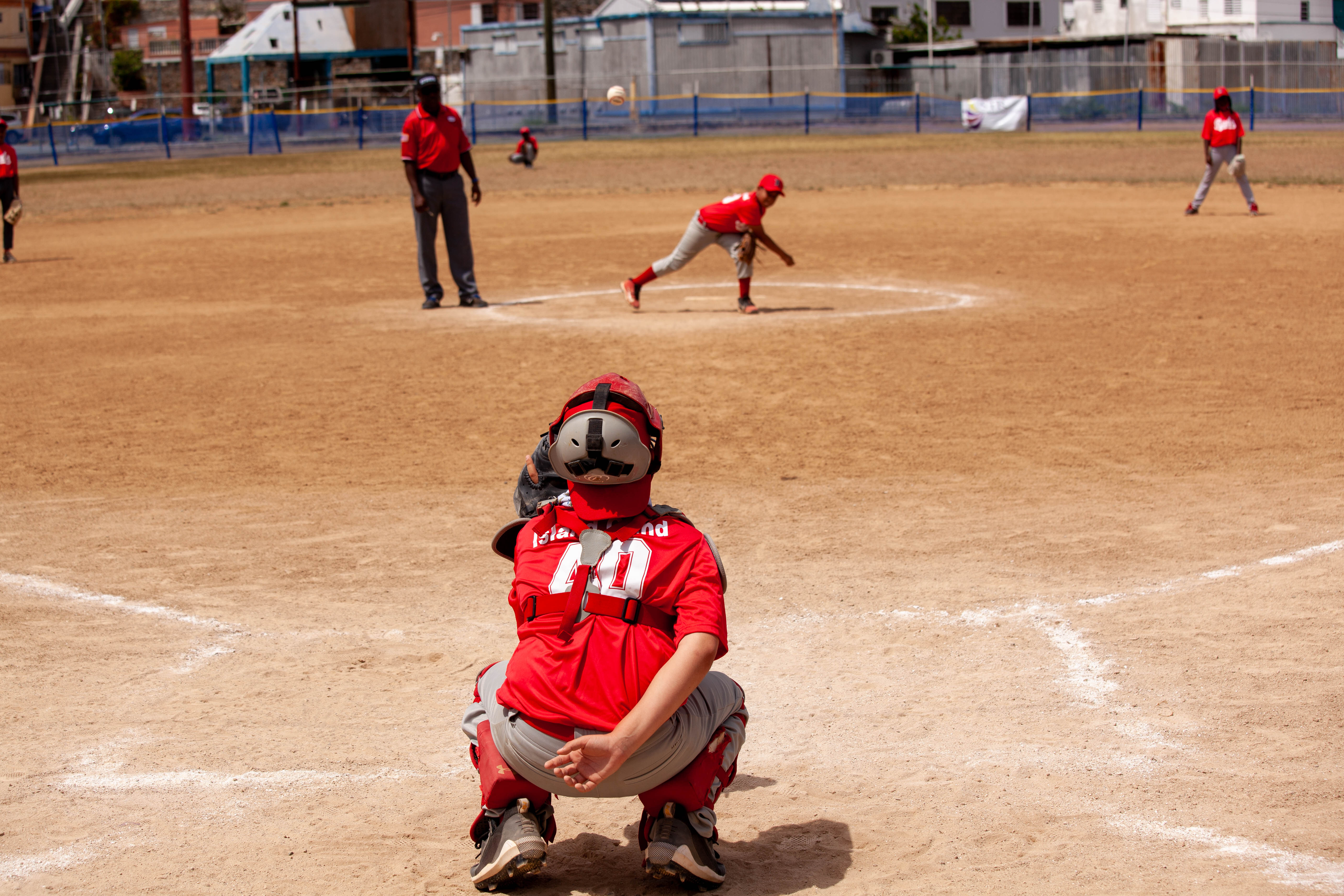 Catcher sets behind home plate as pitcher delivers ball.