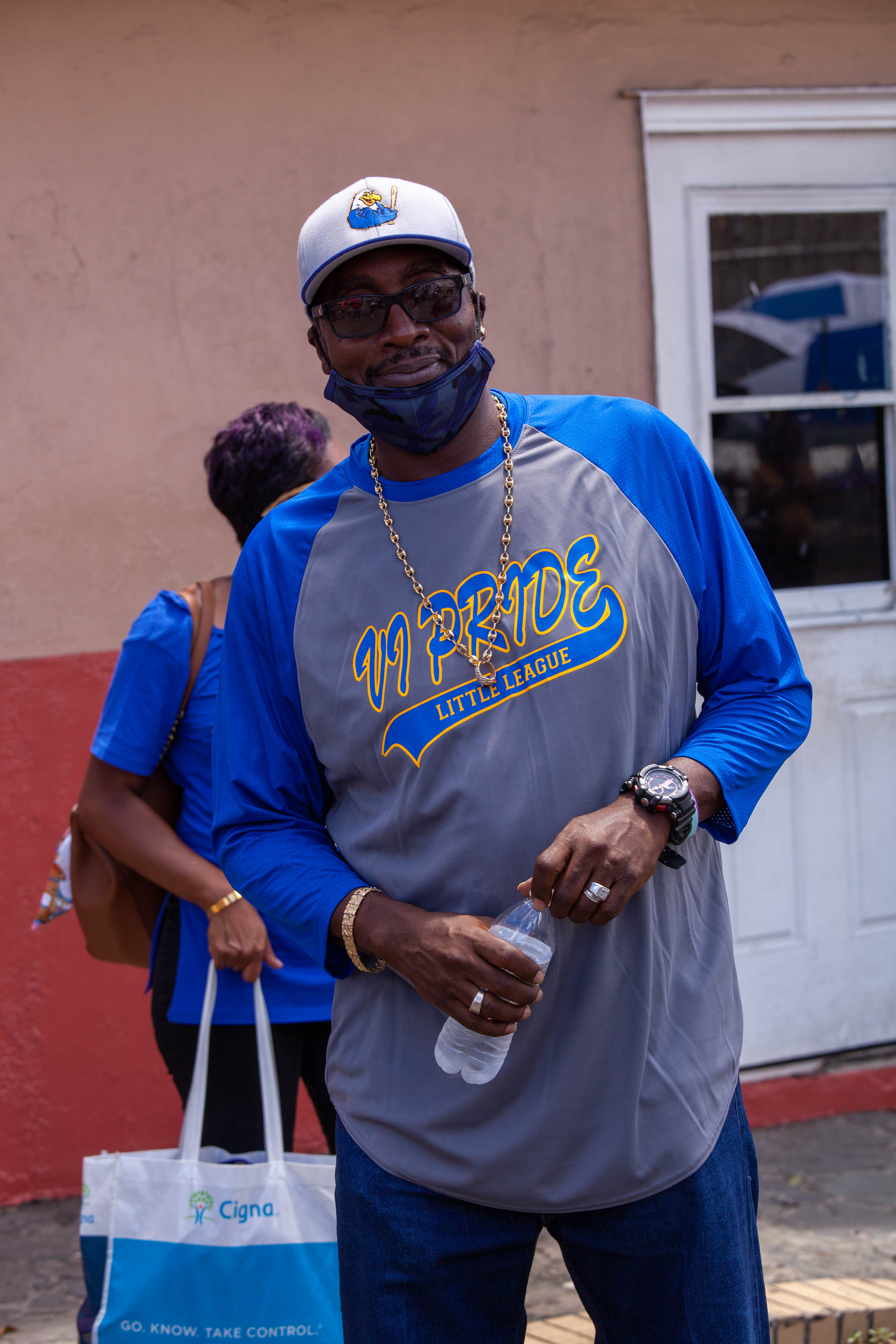 Community members watch from the ballpark edge during Little League opening ceremonies.