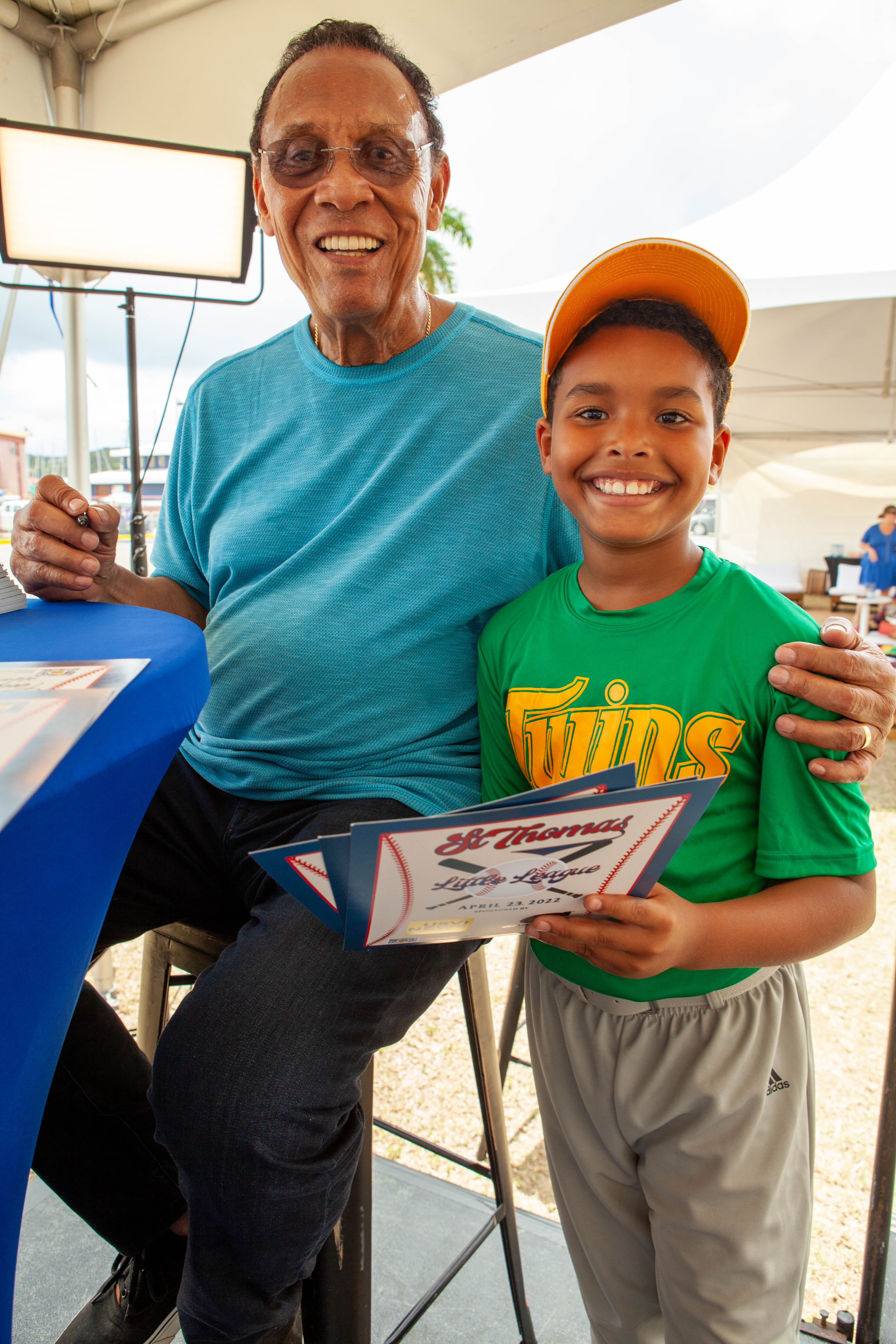 Tony Perez poses with a smiling boy holding a certificate.